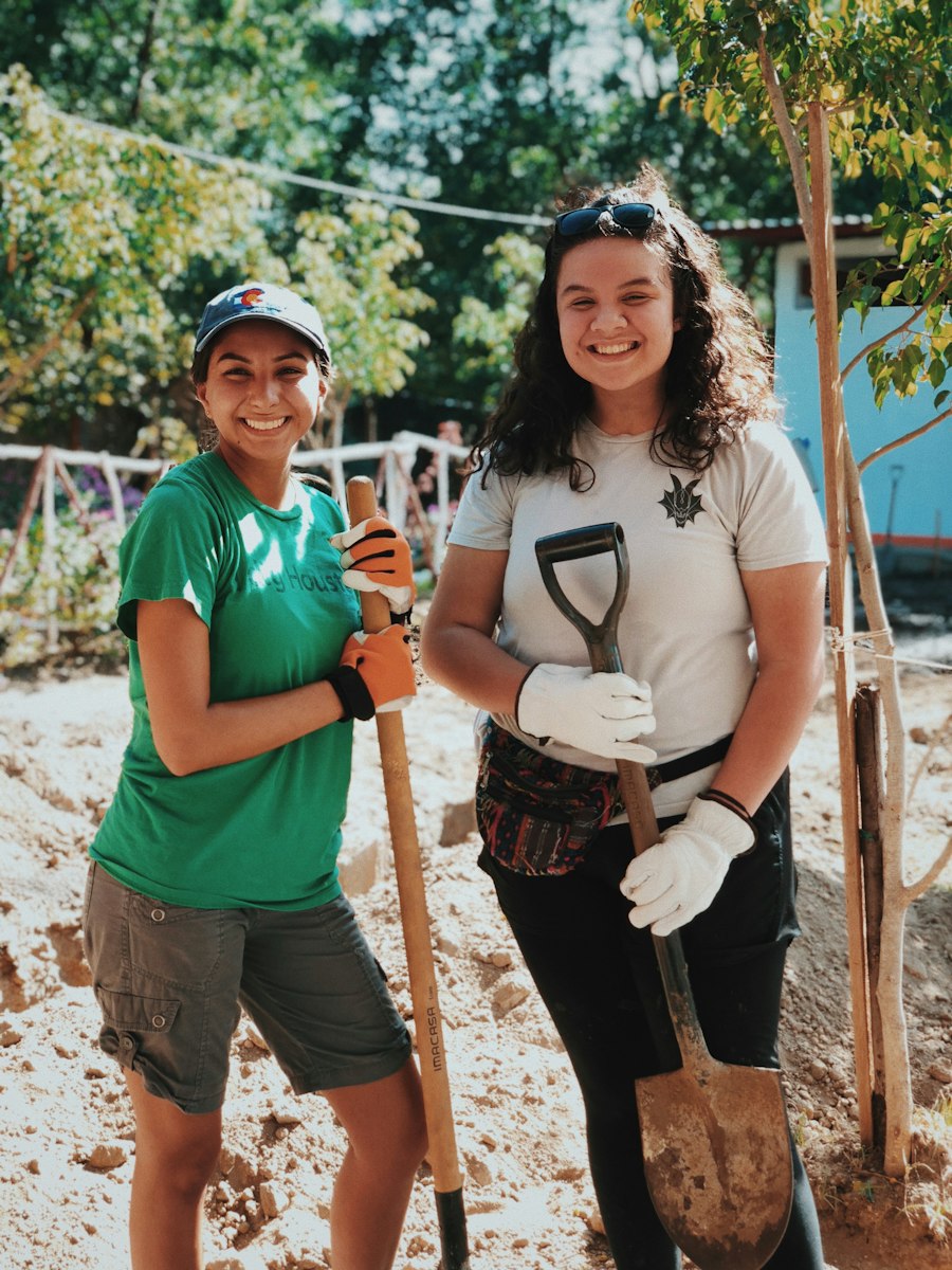 Two smiling volunteers with garden tools